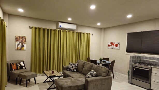 Una sala de estar moderna con un sofá modular, una mesa de comedor y una zona de cocina con estufa.