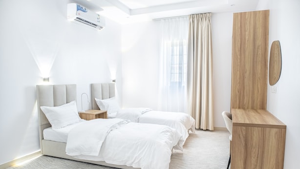 A modern hotel room with a large bed, a wooden nightstand, a desk, and a large mirror. - Badrani A - Qaswarah Residence  (Madinah)