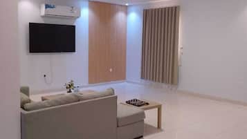 A modern living room with a sofa, a flat-screen TV, and a wooden accent wall.