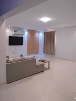 Una sala moderna con sofá, televisor de pantalla plana y una pared de acento de madera.