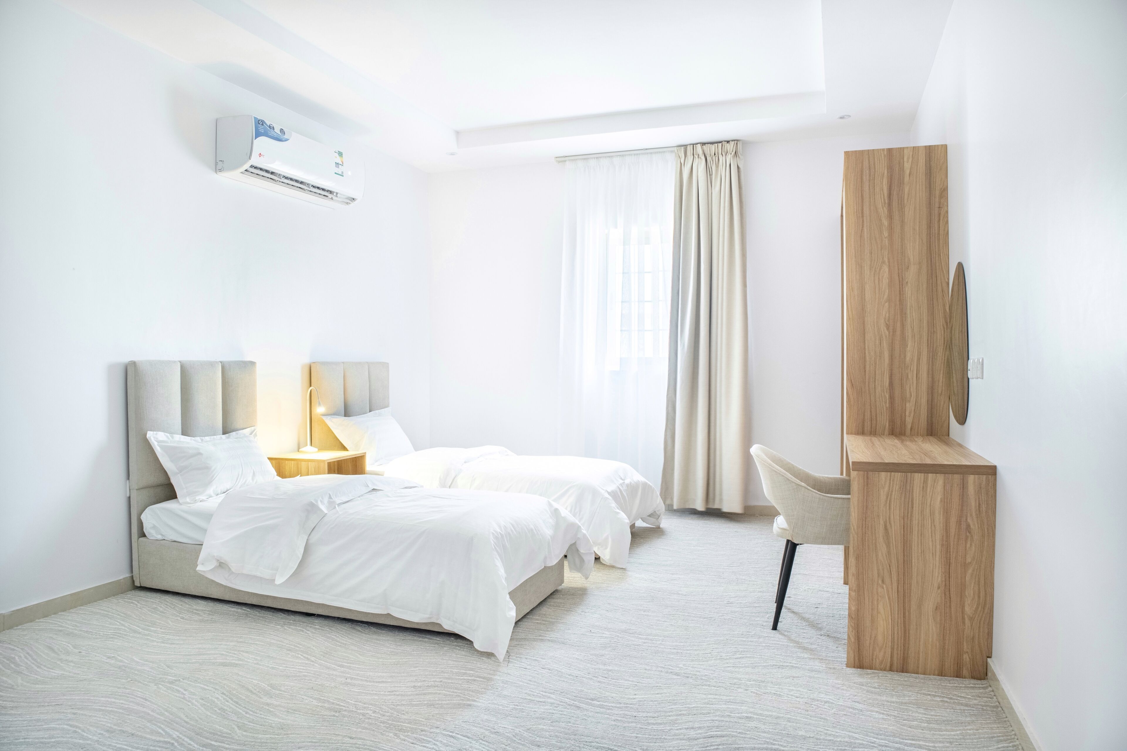 Une chambre d’hôtel moderne équipée d’un lit, de tables de chevet, d’un bureau et d’une armoire.