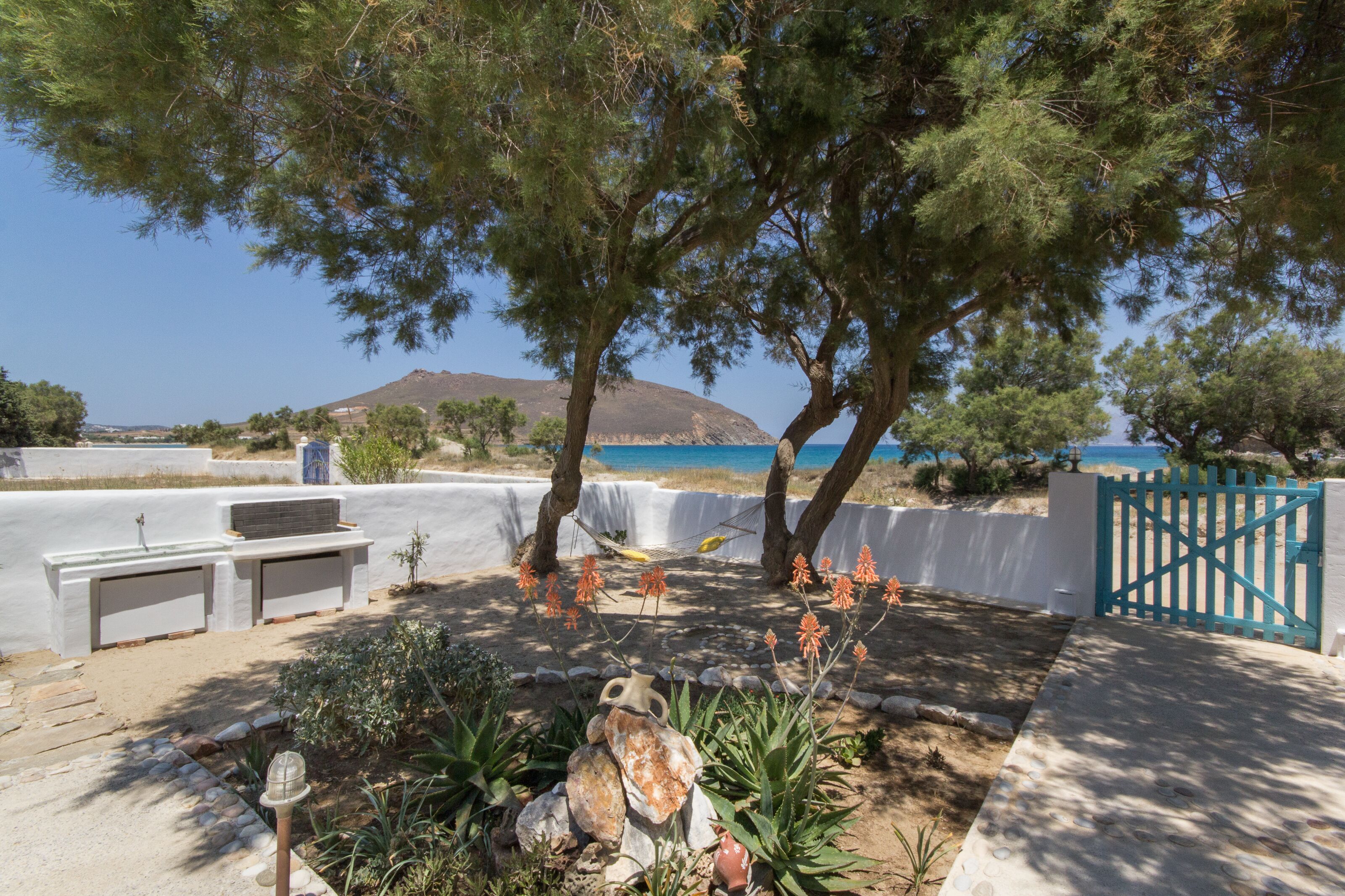 Ein Garten mit weißer Mauer, einer Hängematte und Blick auf das Meer.