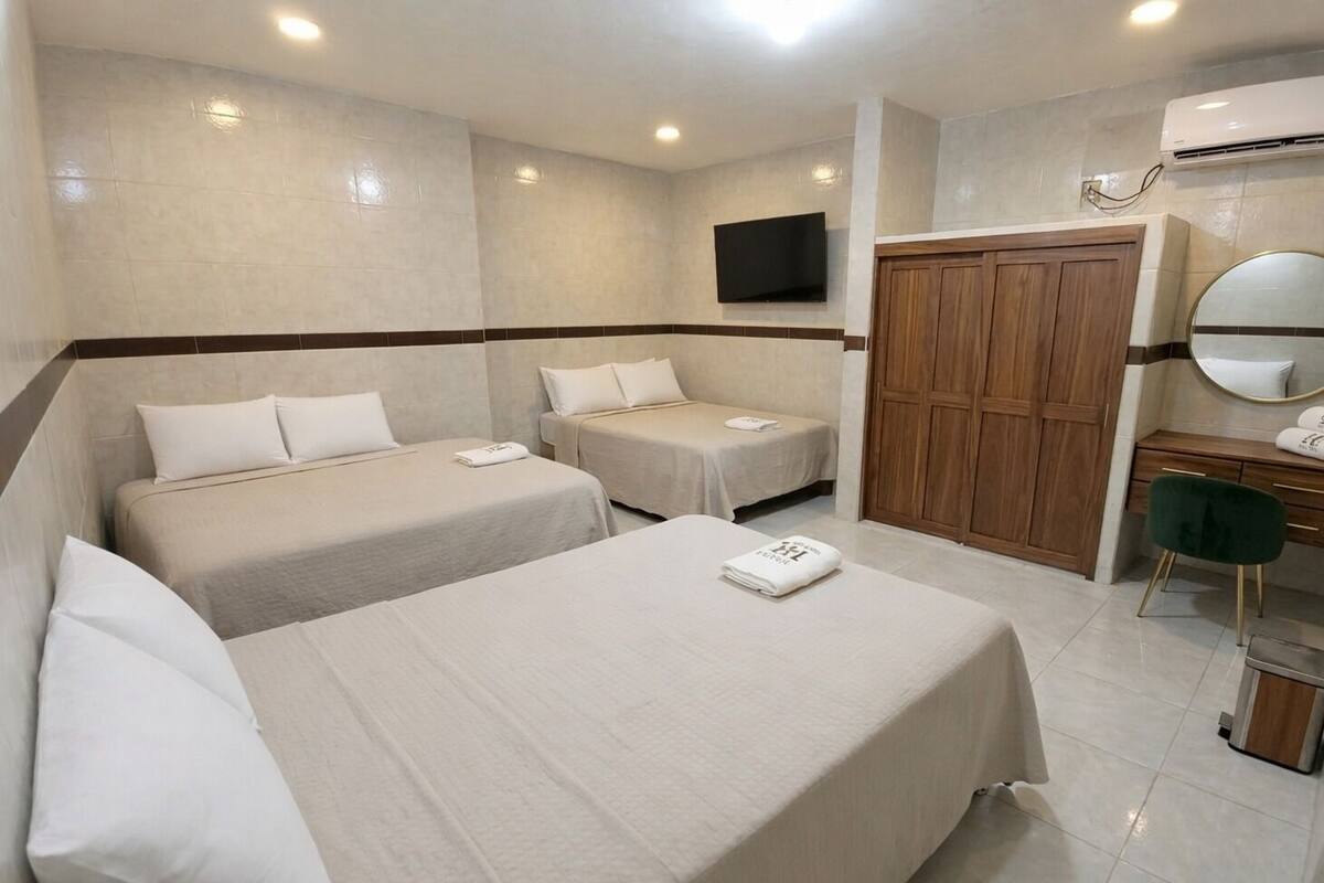 A hotel room with two beds, a desk with a chair, a wardrobe, and a TV mounted on the wall.