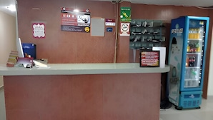 Un mostrador de recepción con una máquina expendedora azul a la derecha.
