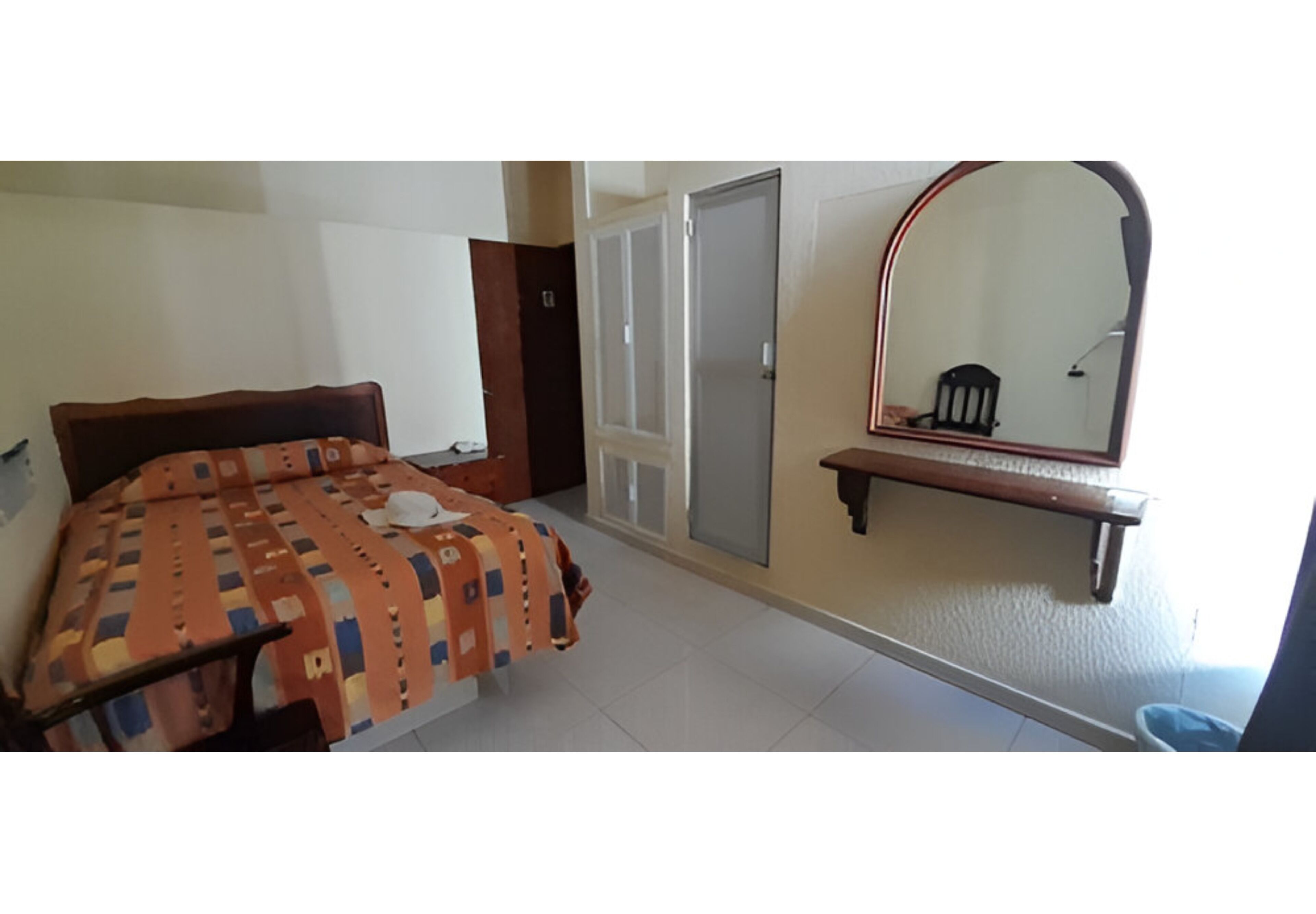 Une chambre à coucher avec un lit, une armoire, un miroir et une petite table.