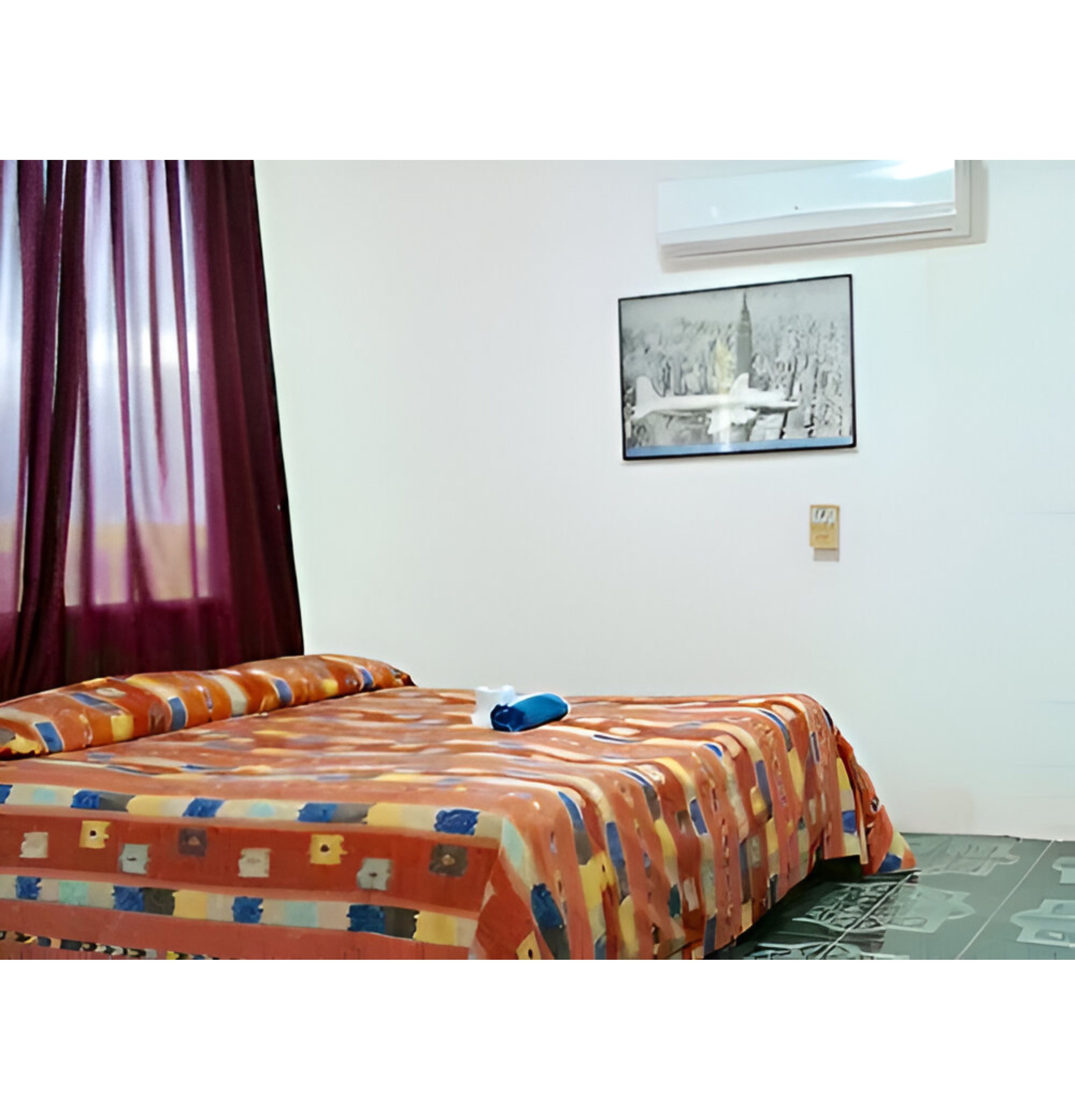 Ein Zimmer mit einem Bett, einem Fenster und einem Wandbild.