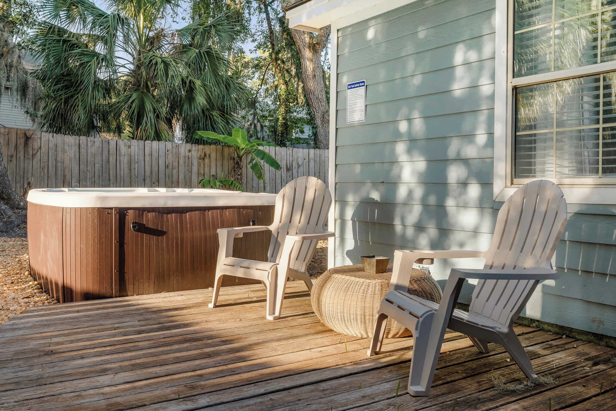 Eine Holzterrasse mit zwei Adirondack-Stühlen und einem Whirlpool.