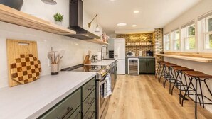 A modern kitchen with wooden countertops, a built-in stove, and a bar area with stools.