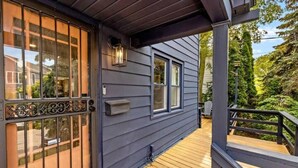 A wooden deck with a railing, a mailbox, and a lantern on the exterior wall of a house.