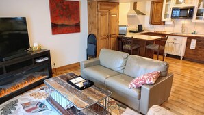Un salon comprenant un téléviseur, une cheminée, un canapé et une table basse.
