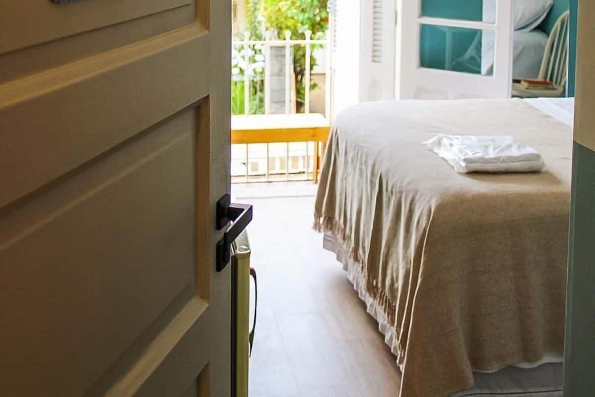 A bedroom with a bed, a wardrobe, and a balcony.