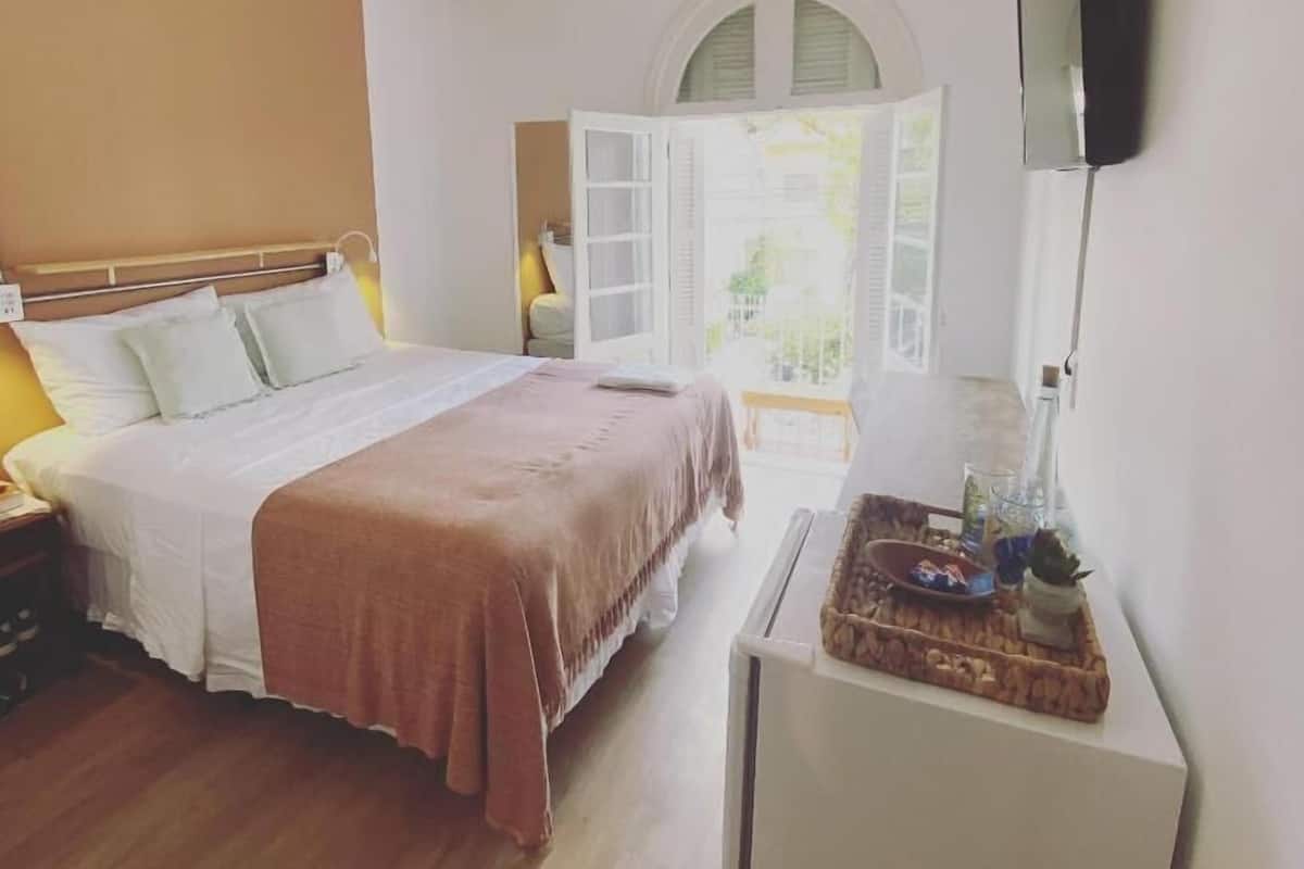 A bedroom with a bed, bedside table, and a small desk with a lamp.