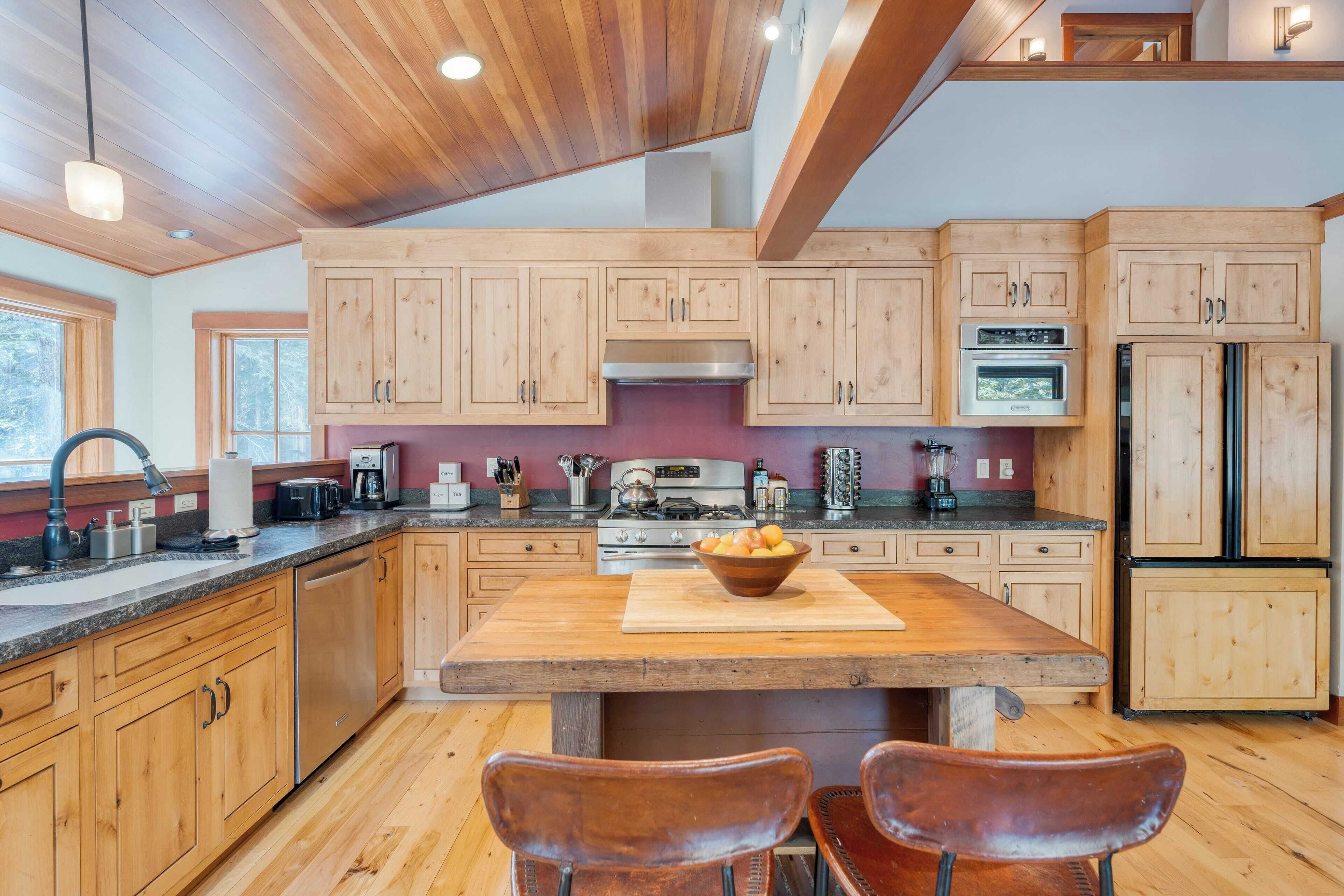A modern kitchen with wooden cabinets, a central island, and stainless steel appliances.