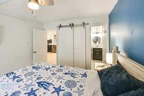 Ein Schlafzimmer mit Bett, Kleiderschrank und einem durchgegangenen Türrahmen erreichbarem Badezimmer.
