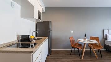 A modern kitchen with a built-in stove, microwave, and refrigerator. There is a dining table with two chairs and a small island with a sink.
