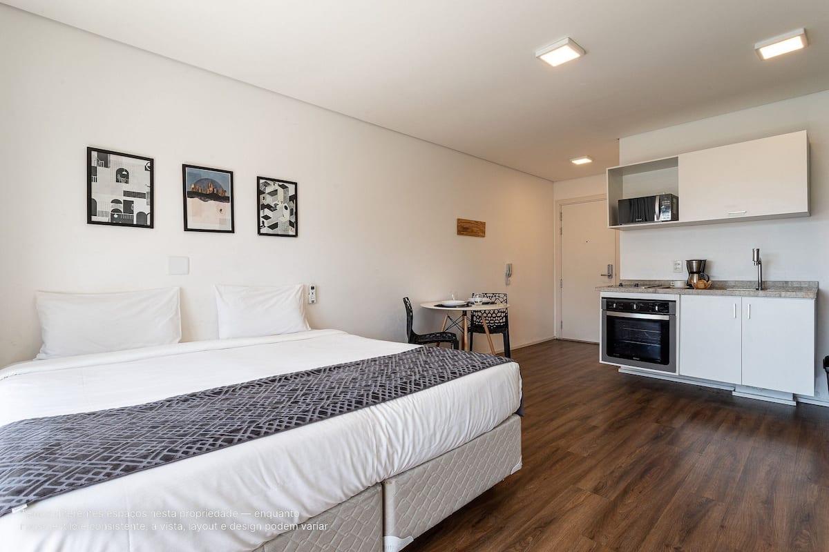 Une chambre d’hôtel moderne dotée d’un grand lit, d’une petite kitchenette et d’un coin repas.