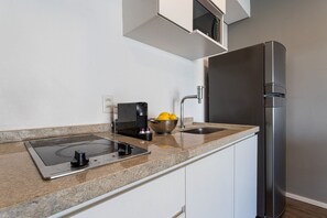 Une cuisine moderne dotée d’une plaque de cuisson à induction intégrée, d’un réfrigérateur en acier inoxydable et d’un évier à deux bacs.