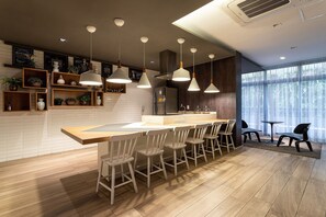 Une cuisine moderne dotée d’un îlot central, de tabourets de bar, de luminaires suspendus et offrant une vue sur l’extérieur grâce à de grandes fenêtres.