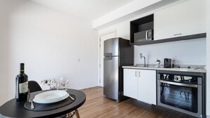 A modern kitchen with a built-in oven, a refrigerator, and a microwave. - Setin Downtown Genebra by Viva - Apartamentos completos na Bela Vista com piscina (São Paulo)
