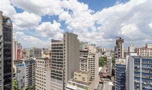 A high-rise urban area with multiple buildings, including a prominent tall structure with a flat roof and a shorter building with a sloped roof. - Setin Downtown Genebra by Viva - Apartamentos completos na Bela Vista com piscina (São Paulo)