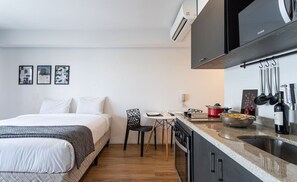 Une chambre d’hôtel de taille réduite, comprenant un lit, une petite table à manger et un coin cuisine.