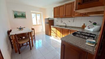 Una cucina con mobili in legno, un fornello a gas, un lavello e un tavolo da pranzo con sedie.