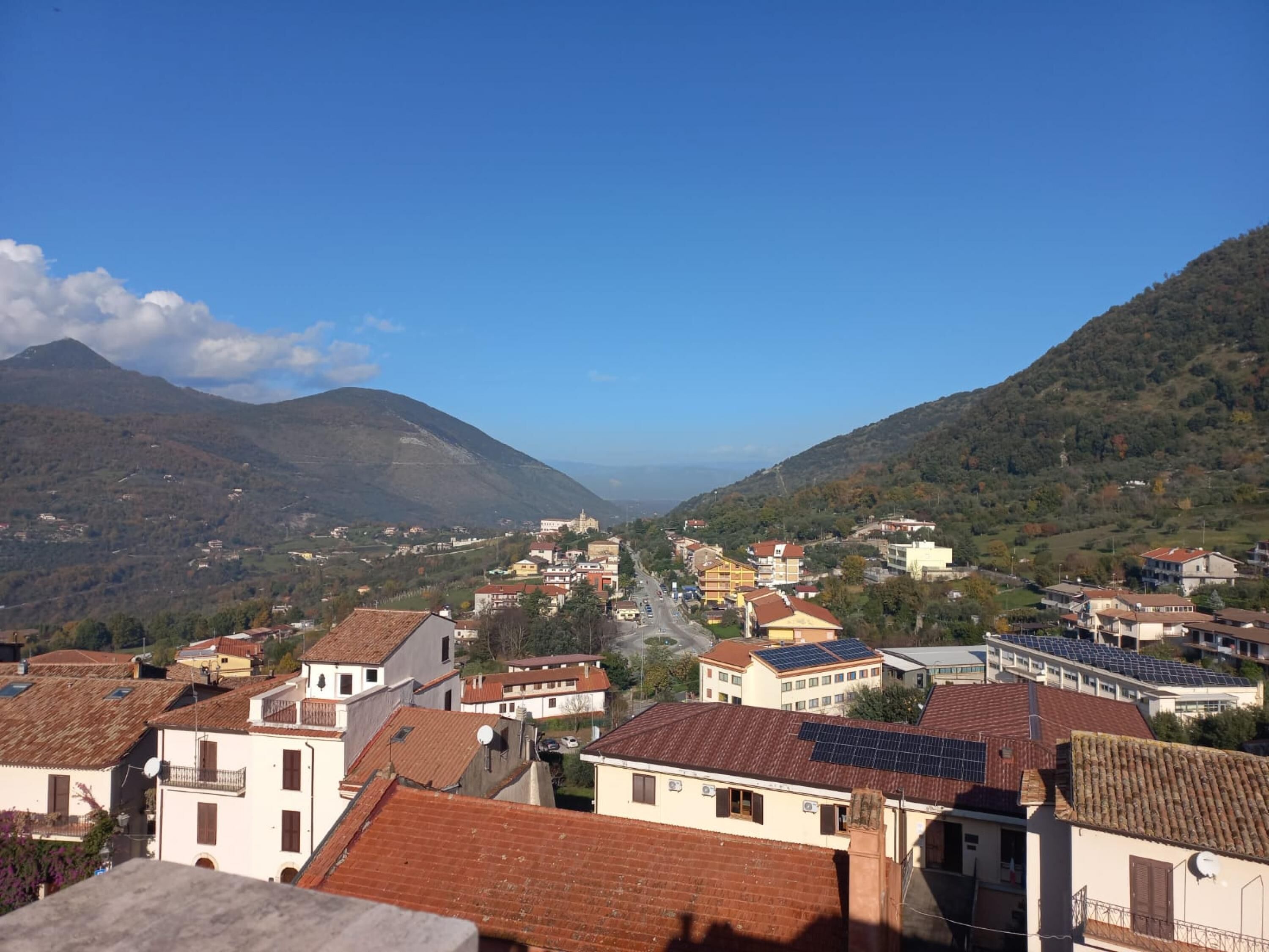 Une ville où se côtoient des bâtiments traditionnels et modernes, avec un ciel dégagé et un paysage montagneux en toile de fond.