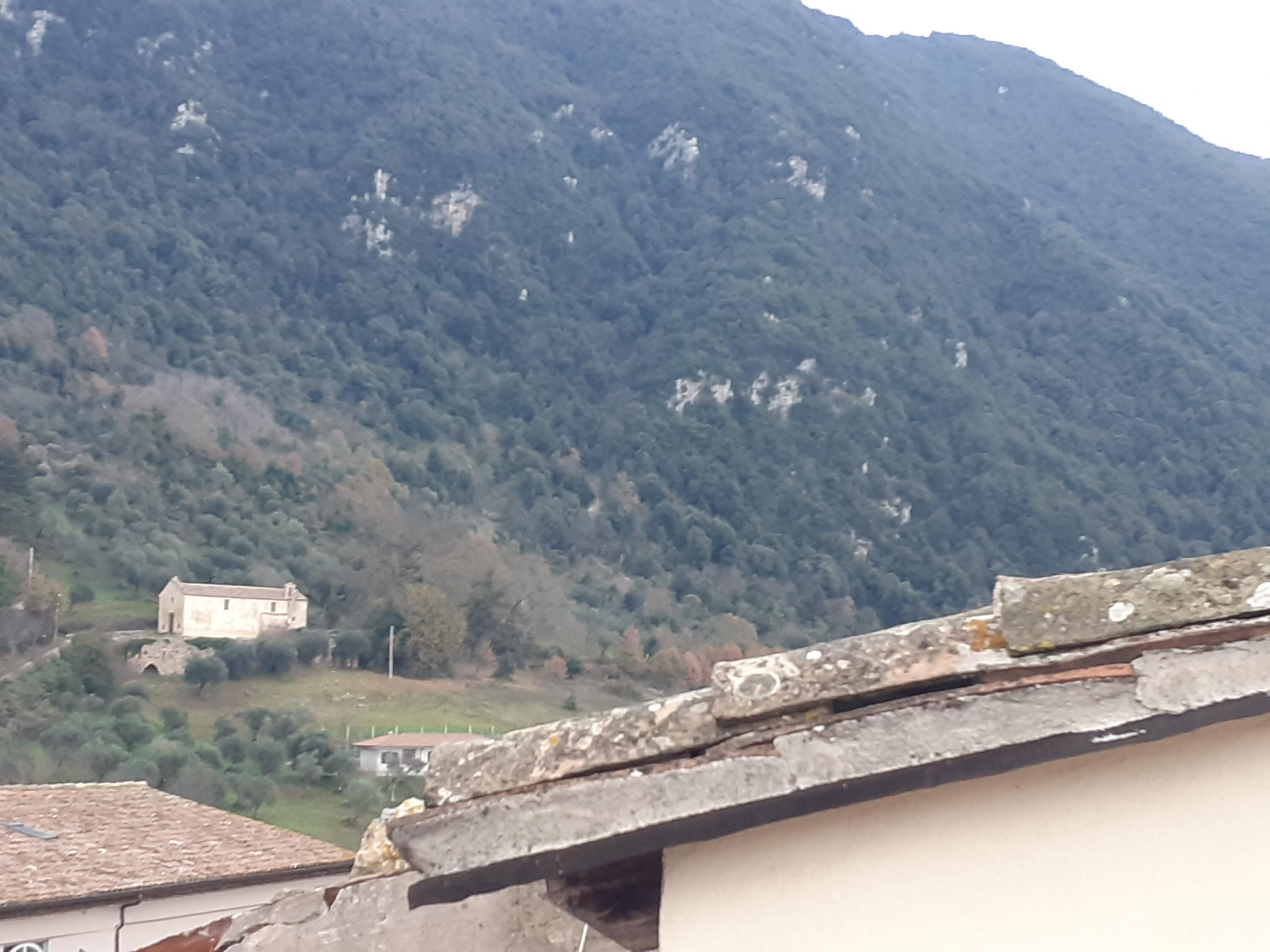 A mountainous landscape with a small building in the valley.