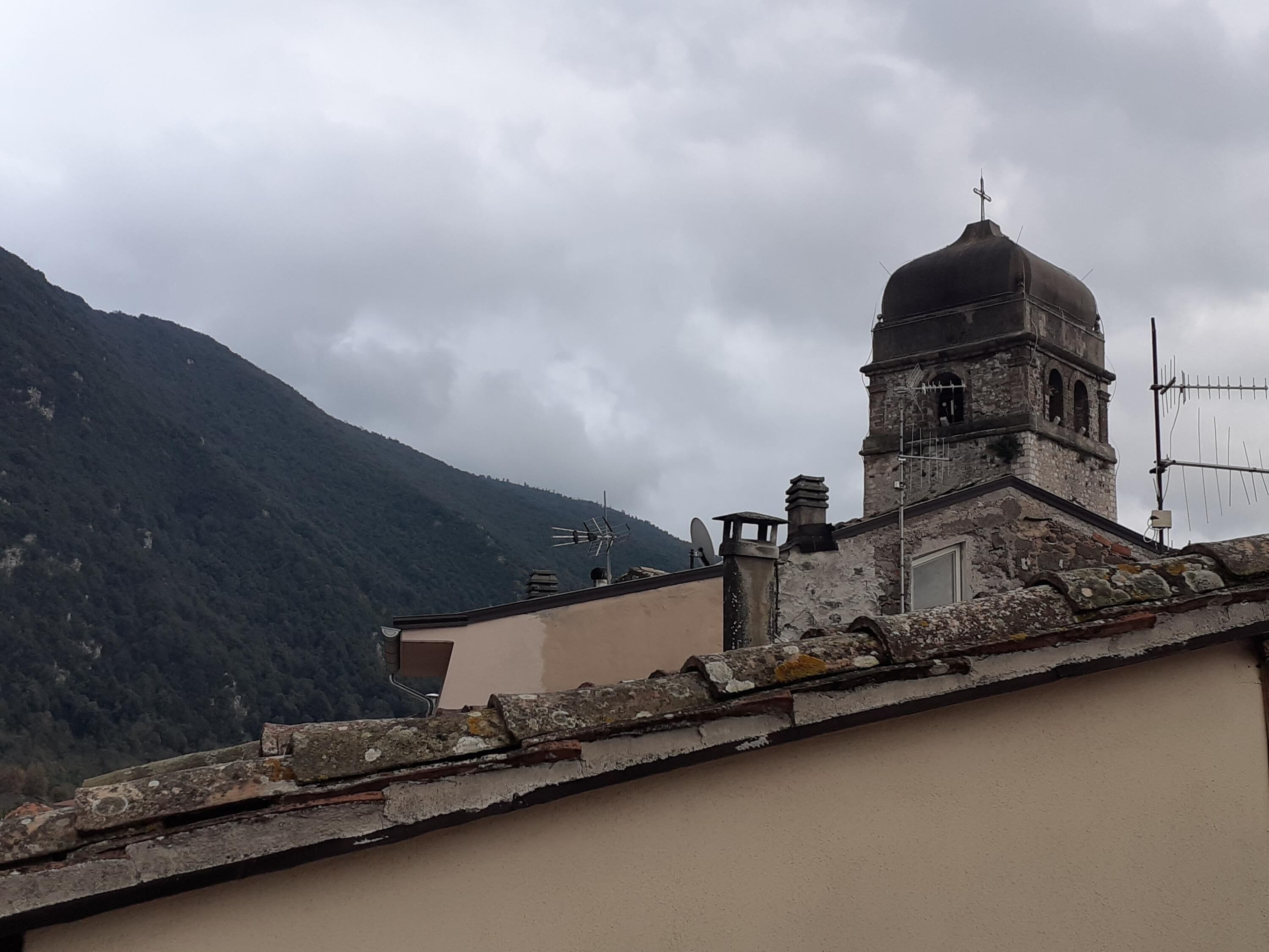 A building with a bell tower and a mountain in the background.