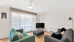 Ein Wohnzimmer mit Deckenventilator, Flachbildfernseher und zwei Sofas.