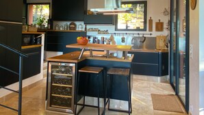 Cocina moderna con isla central, espacio para vinos empotrado y un amplio ventanal que proporciona luz natural.