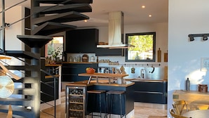 Una cocina moderna con una isla central, un enfriador de vino integrado y una escalera en espiral.