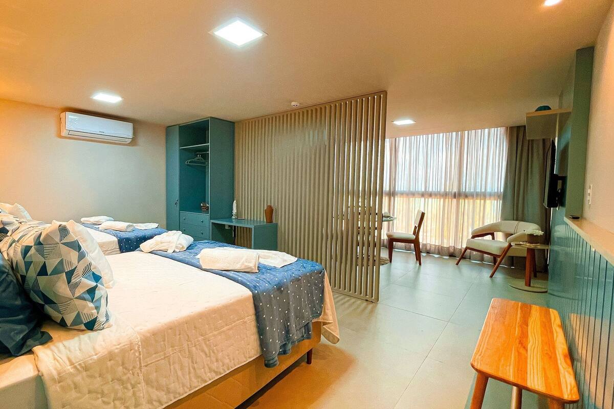 Une chambre d’hôtel avec deux lits, un bureau, une chaise, une télévision et une fenêtre avec des rideaux.