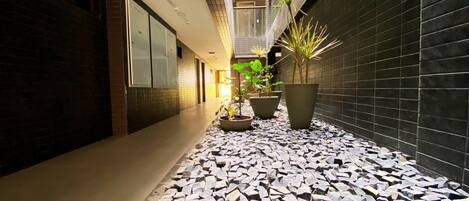 A corridor with a tiled floor, potted plants, and a modern interior design.