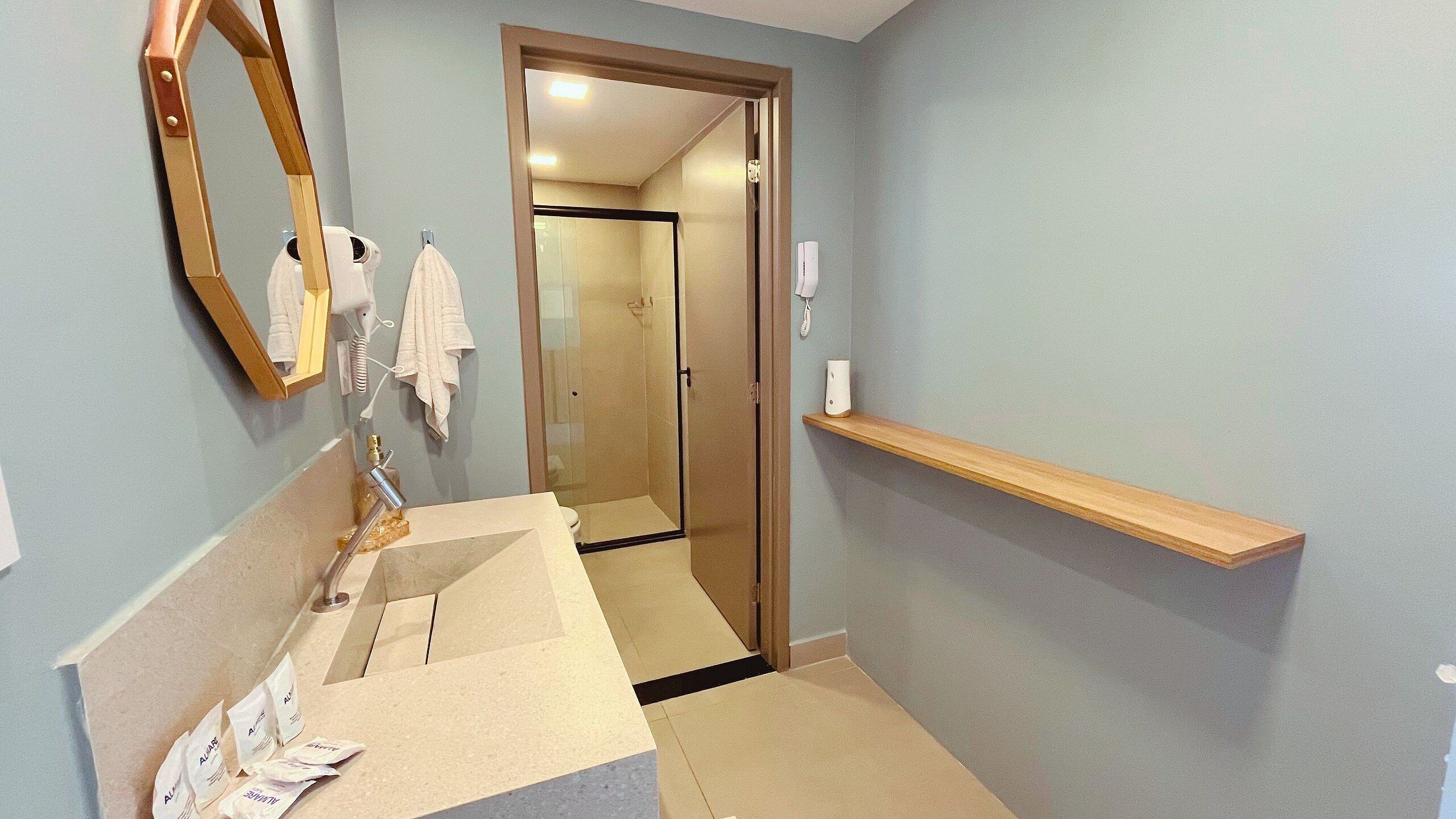 A bathroom with a sink, mirror, towel rack, and a shower area.
