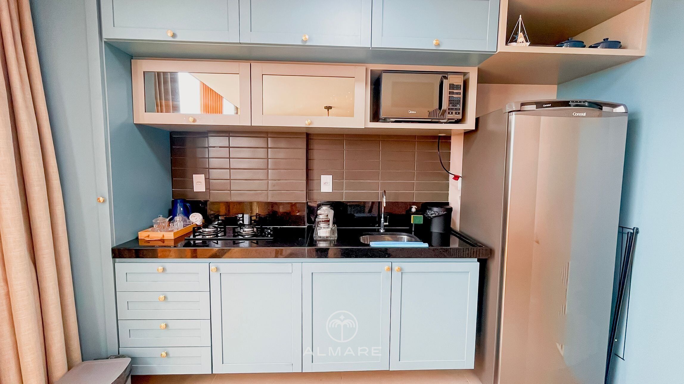 A compact kitchen with a microwave, stove, and refrigerator.