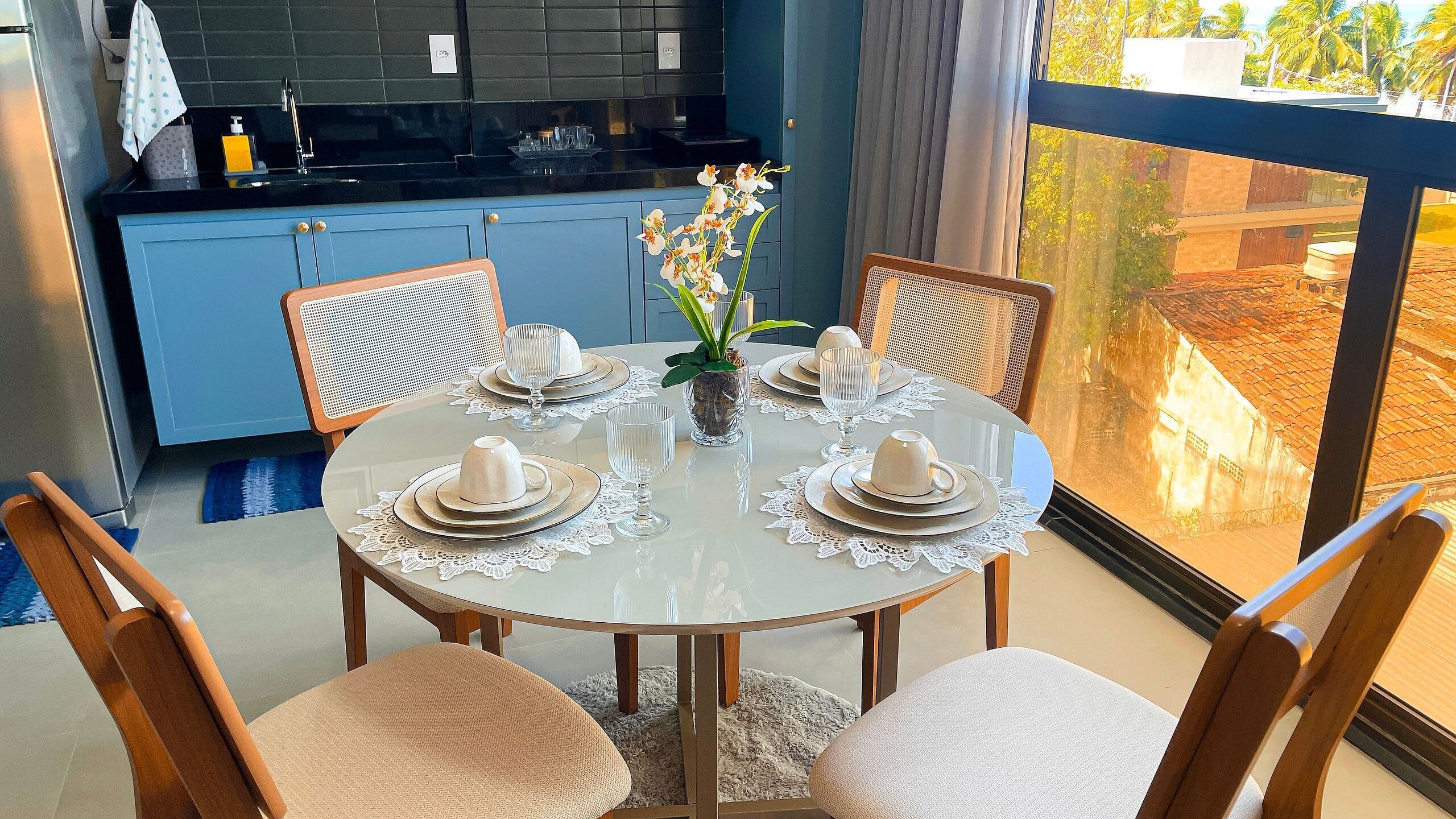 A dining area with a round table set for four, surrounded by wooden chairs.