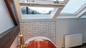 Ein Badezimmer mit Oberlicht, Badewanne und Heizkörper.