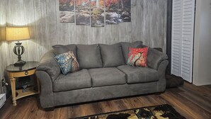 Un sofá gris con cojines de colores, una lámpara y una pared con cuatro cuadros enmarcados.
