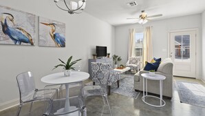 A modern living room with a dining area, a sofa set, a TV, and artwork on the walls.