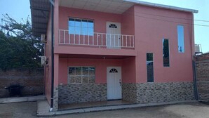 A two-story building with a balcony, a door, and a window.