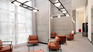 A modern waiting area with leather chairs, a high ceiling, and large windows. - Vossa Bossa VN Ueno (São Paulo)