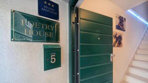 Una porta verda amb un cartell a la part superior que diu "POETRY HOUSE" i un cartell més petit que indica "STUDIO APARTMAN".