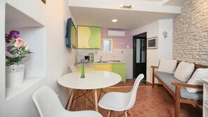 Un espai vital compacte amb zona de menjador, petita cuina i paret decorativa de pedra.