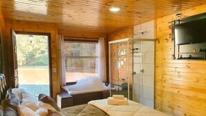 A wooden cabin room with a bed, a glass shower, and a view of a lake. - Refúgio Brisa Serrana - Urubici - SC (Urubici)