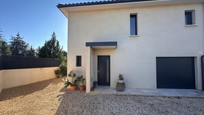 Une maison moderne à deux étages, dotée d’un toit plat, d’une porte d’entrée et d’un garage.