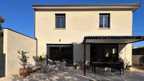 Une maison à deux étages avec une piscine, un espace salon extérieur et une pergola.