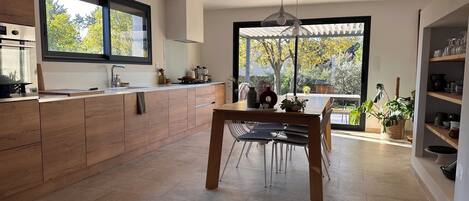 A modern kitchen with wooden cabinetry, a central island, and a dining area with chairs.