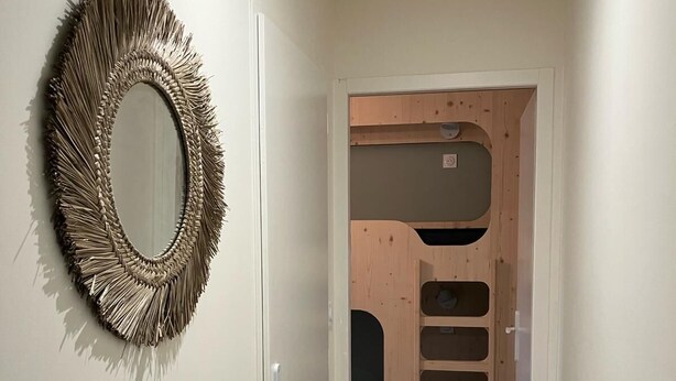 A hallway with a wooden door, a mirror with a fringe design, and a wall with a wooden panel. - Appartement Idéal Famille, Belle VUE Mer, Plage du Capelan Accessible à Pieds! (Bandol)