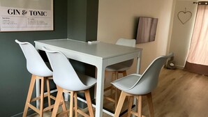 A dining area with a white table and four grey chairs with wooden legs. - Appartement Idéal Famille, Belle VUE Mer, Plage du Capelan Accessible à Pieds! (Bandol)